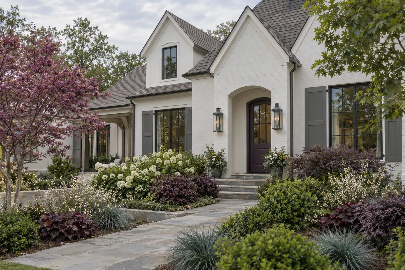 Snowbound white cottage with gray shutters, plum door, and burgundy-and-white planting